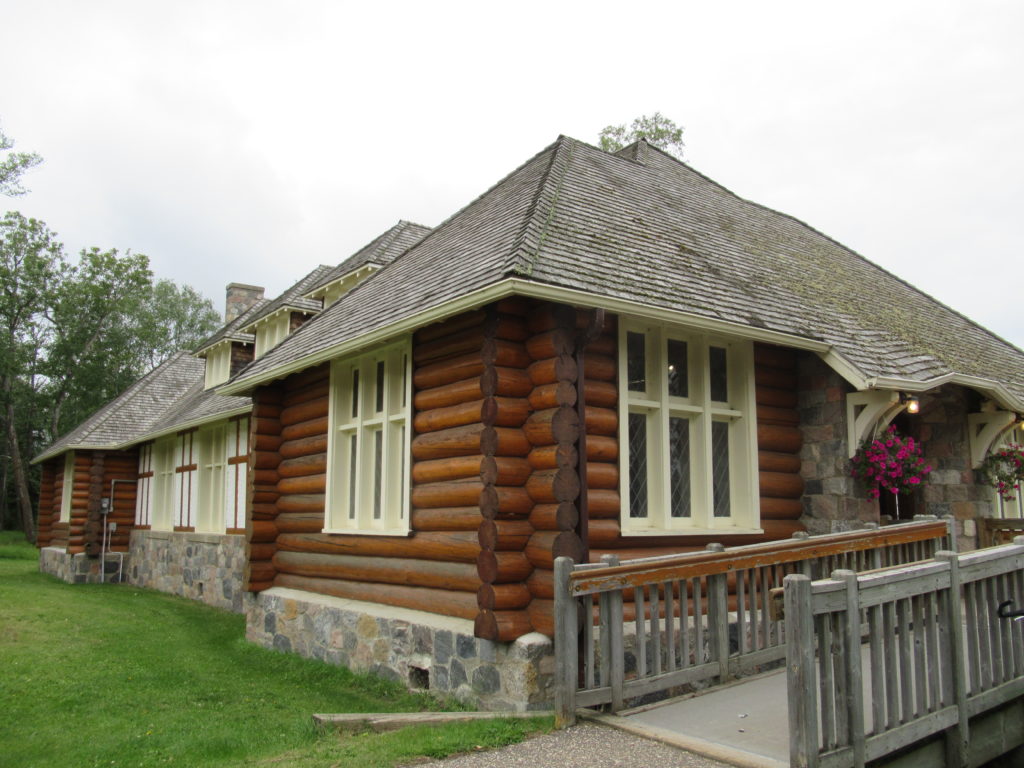 Old log building with wood shingles, horizontal logs and a multi-coloured stone foundation