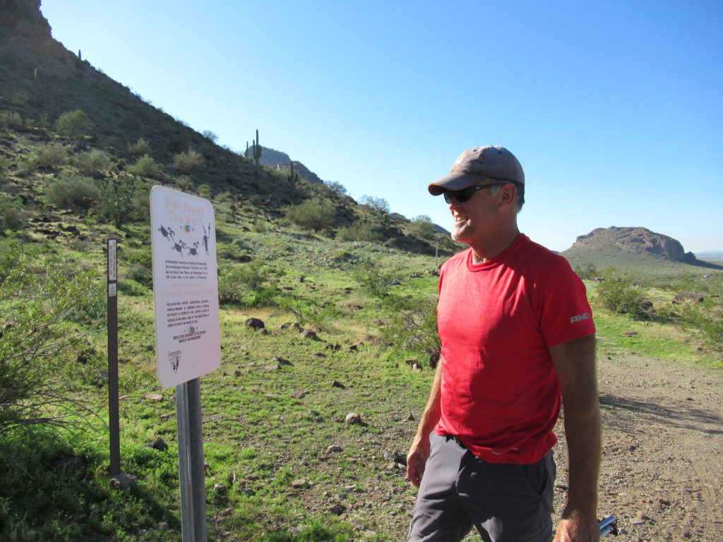 Hiker in Arizona desert looking at archaeological site sign