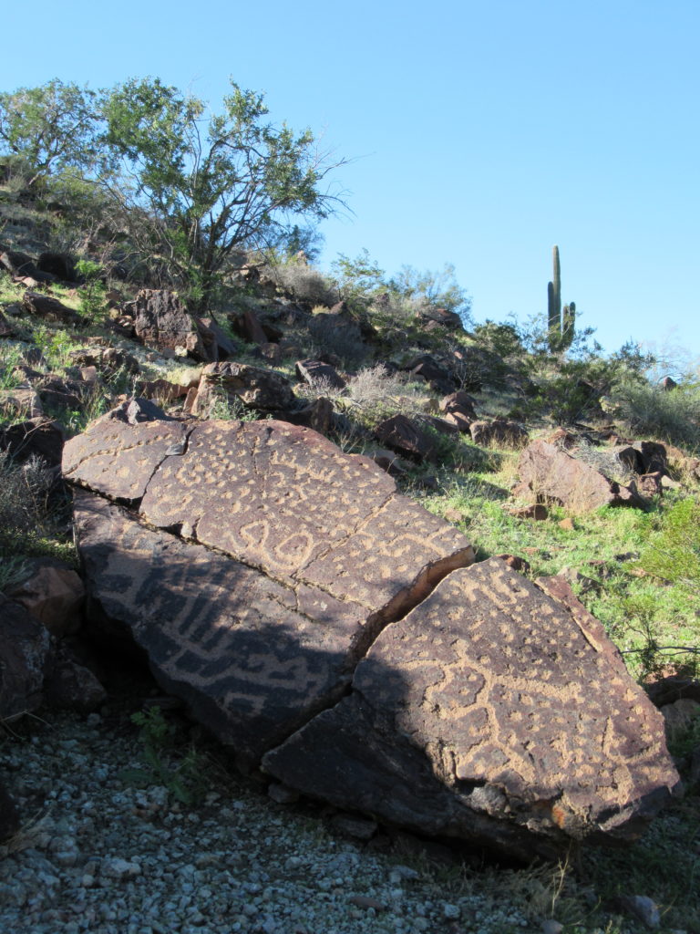 Rock art on larger dark brown boulder in desert