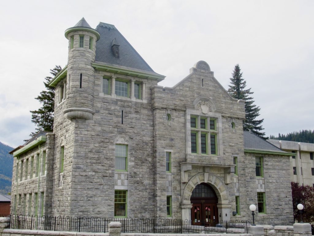 Ornate grey stone building with pale green trim on windows and solid wood doors.