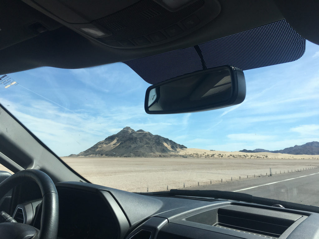 View of lava rock mountains and sand taken from inside truck cab
