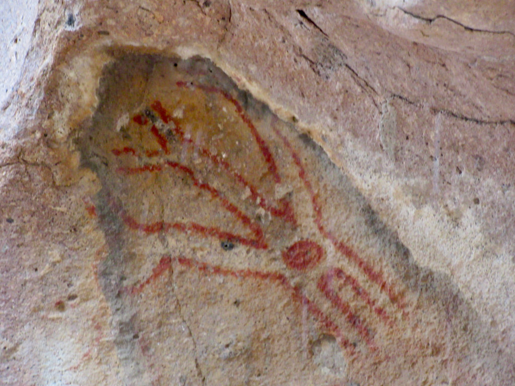 Red line and symbols painted on pinkish rock.
