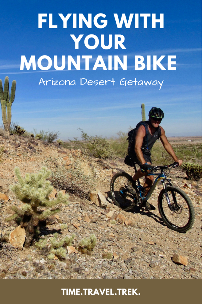 Pin image with man on mountain bike in desert. Text overlay reads "Flying with Your Mountain Bike: Arizona Desert Getaway. Time.Travel.Trek."