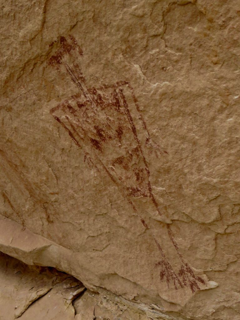 Red human-like figure painted on red sandstone rock wall.