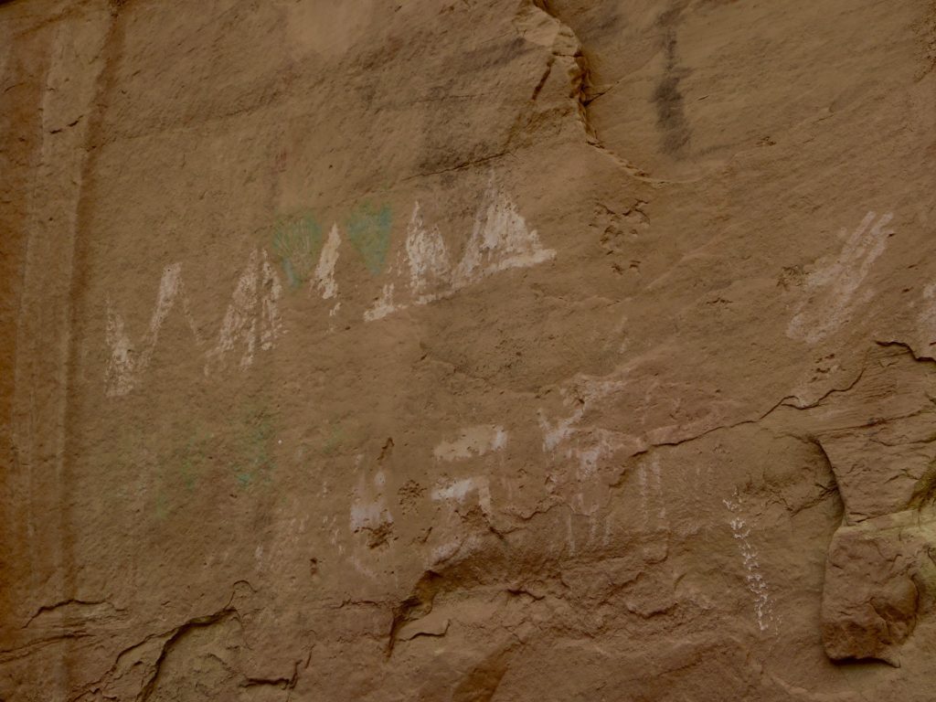 Green, white and red abstract marks on rock wall