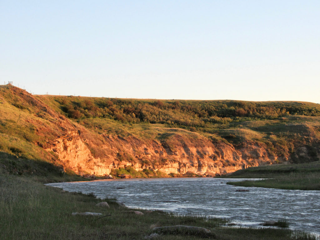 Sandstone cliffs above river glowing in evening light.