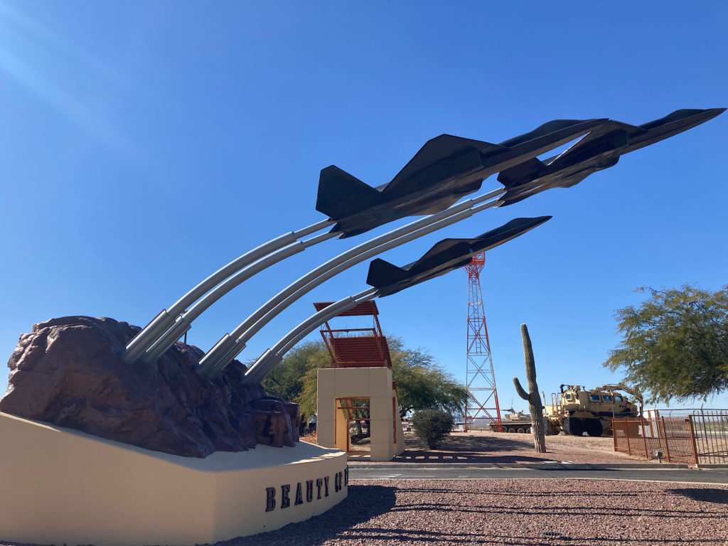 Statue with three fighter jets arcing out of rocky base labelled with words: Beauty of Flight.