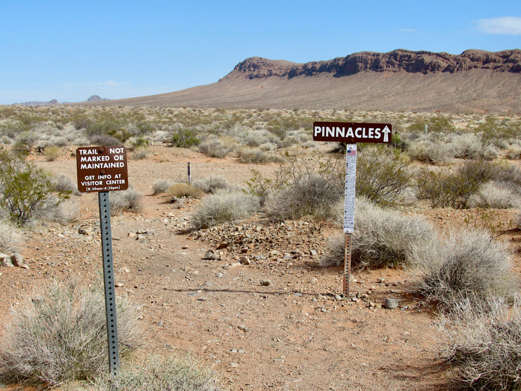 Signposts for Pinnacle trail on sandy path in desert.