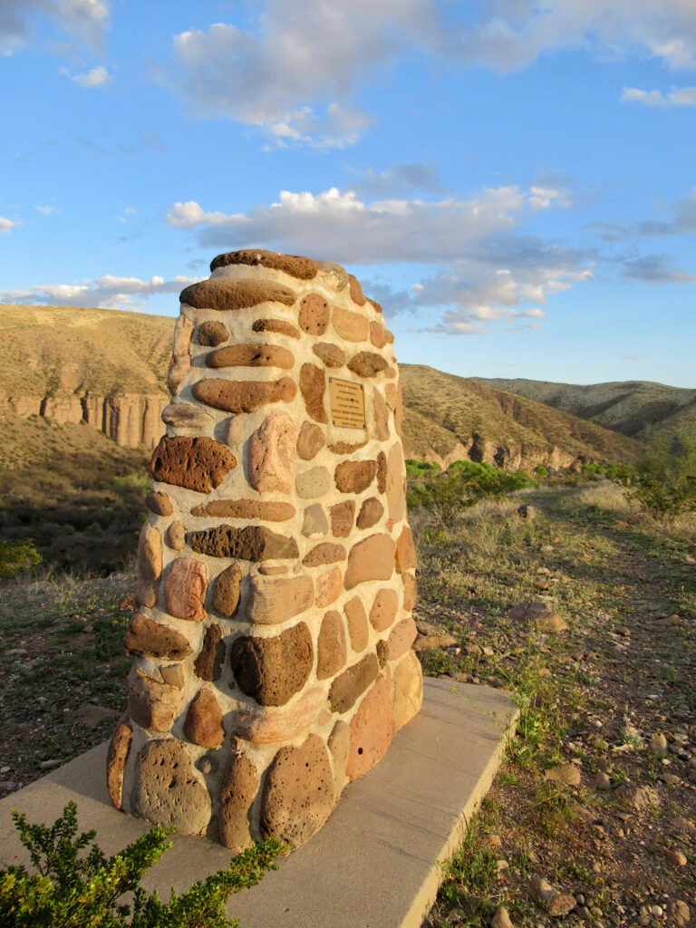 Stone monument with hills in background at sunset.
