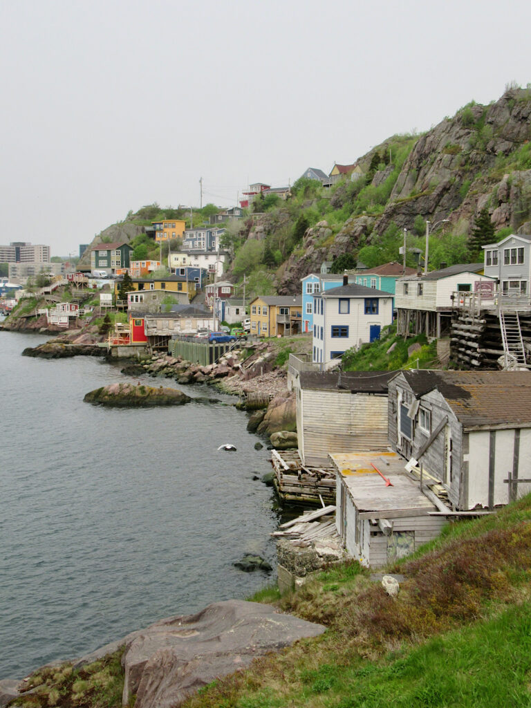Colourful houses perched cliffside beside the water.