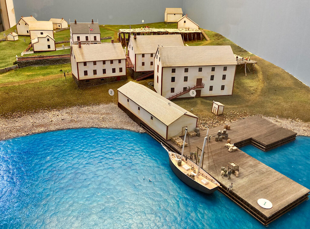Model of white buildings and dock on water's edge.