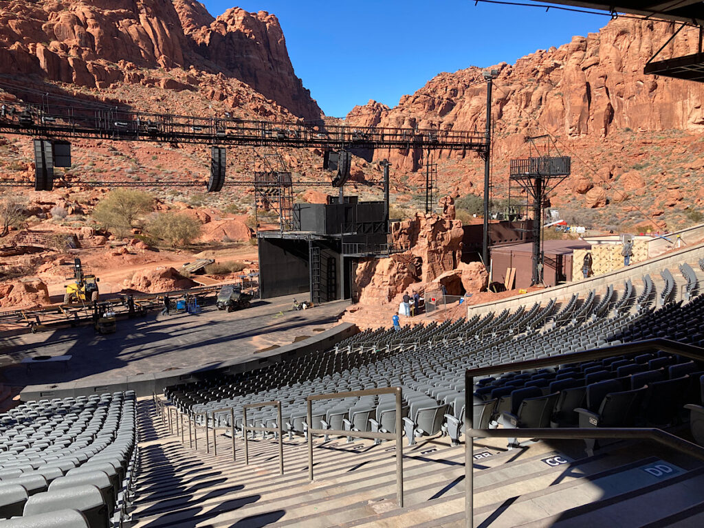 Metal benches overlooking stage with tall cliffs in background. 