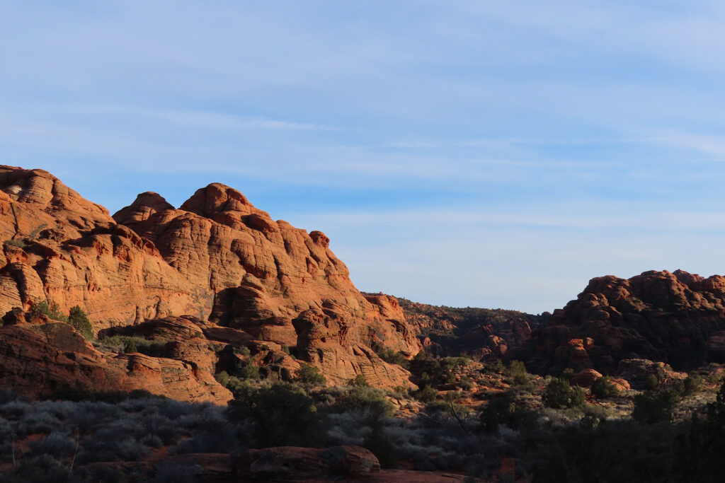 Sunset glow of red sandstone cliffs above Snow Canyon campground in shade.