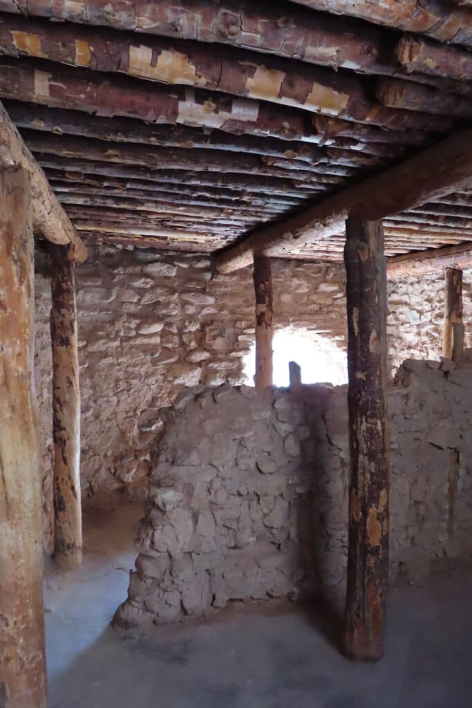 Darkened interior room with stone walls and large wooden beams for support and roof structure.