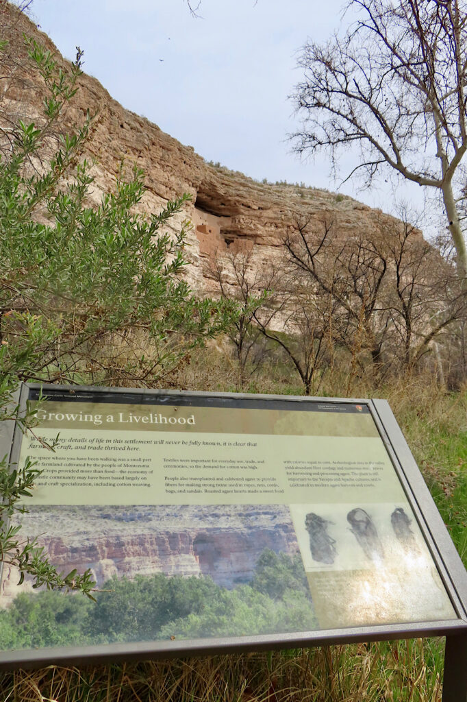 Interpretive sign in front of distant cliffside ruin.