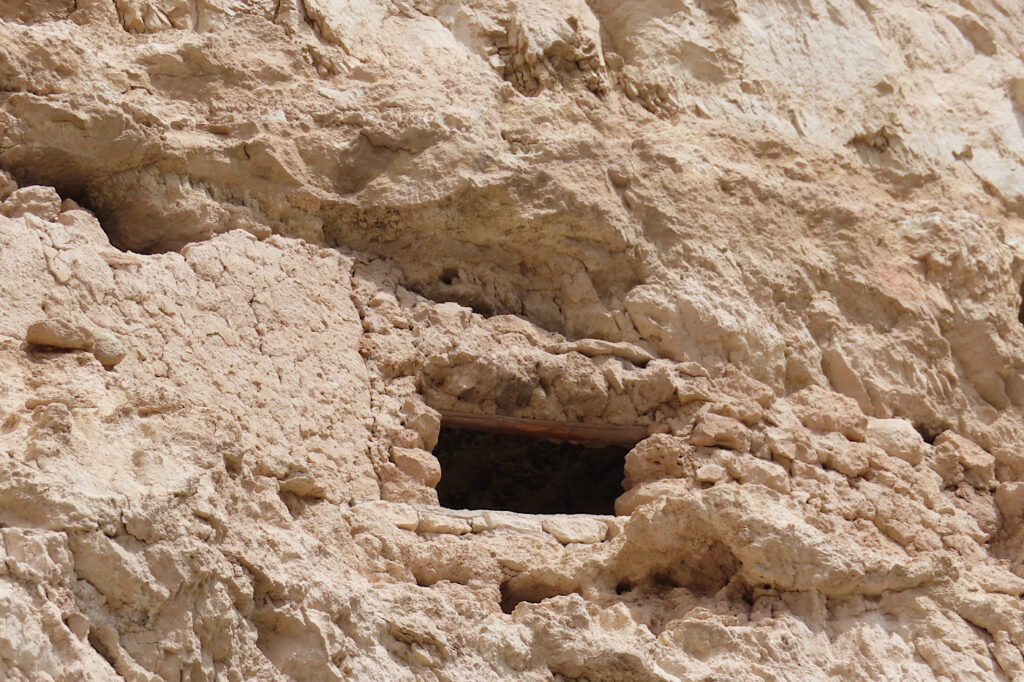 Stone wall with opening to room behind in cliff.