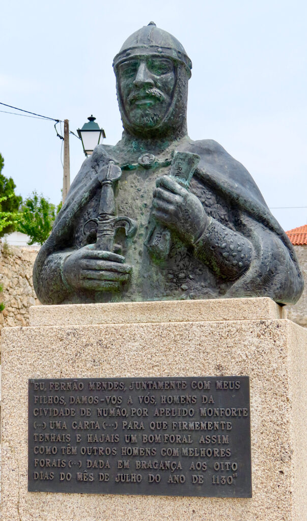 Bronze bust of a knight holding a scroll in one hand.