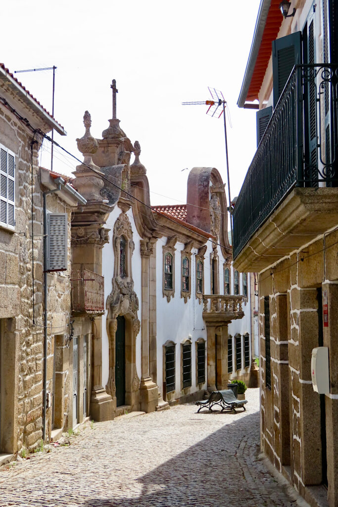 Narrow obblestone street lined with old stone buildings.