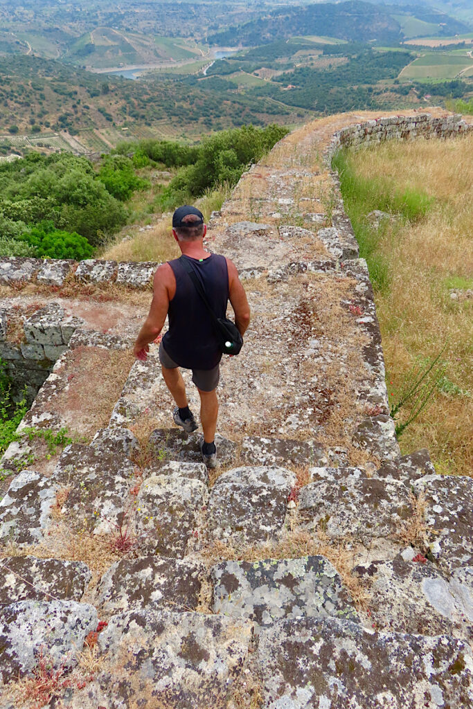 Man in shorts and short sleeved top walking down a stone wall.