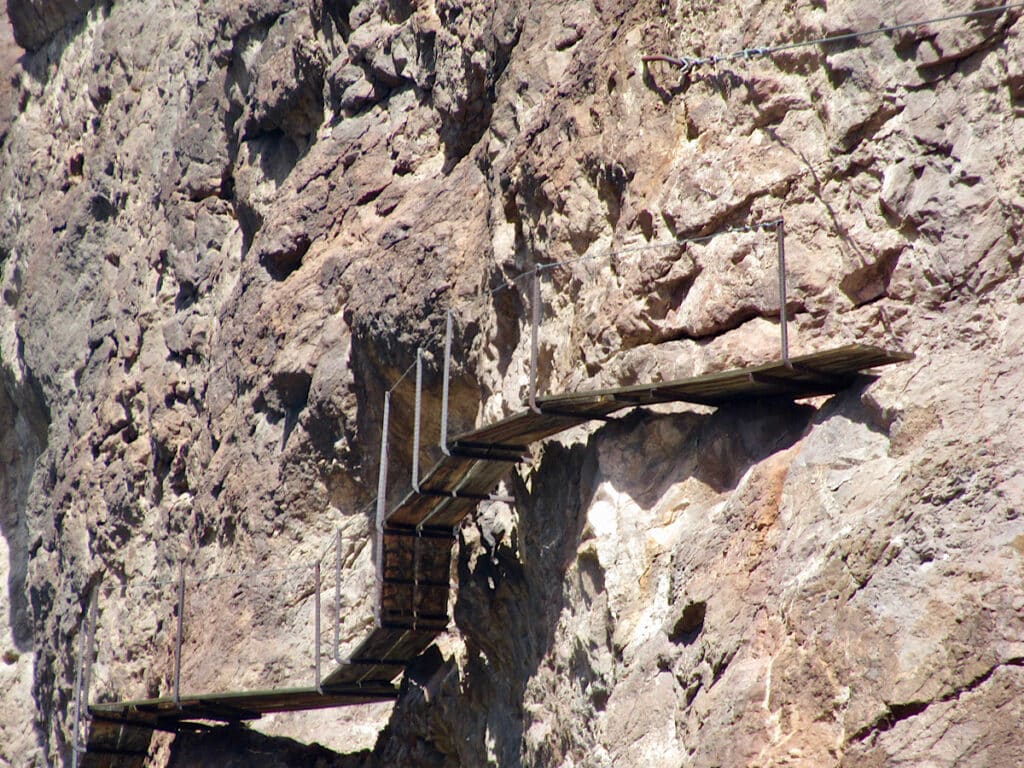 Wooden planks and metal clinging to rock cliff.