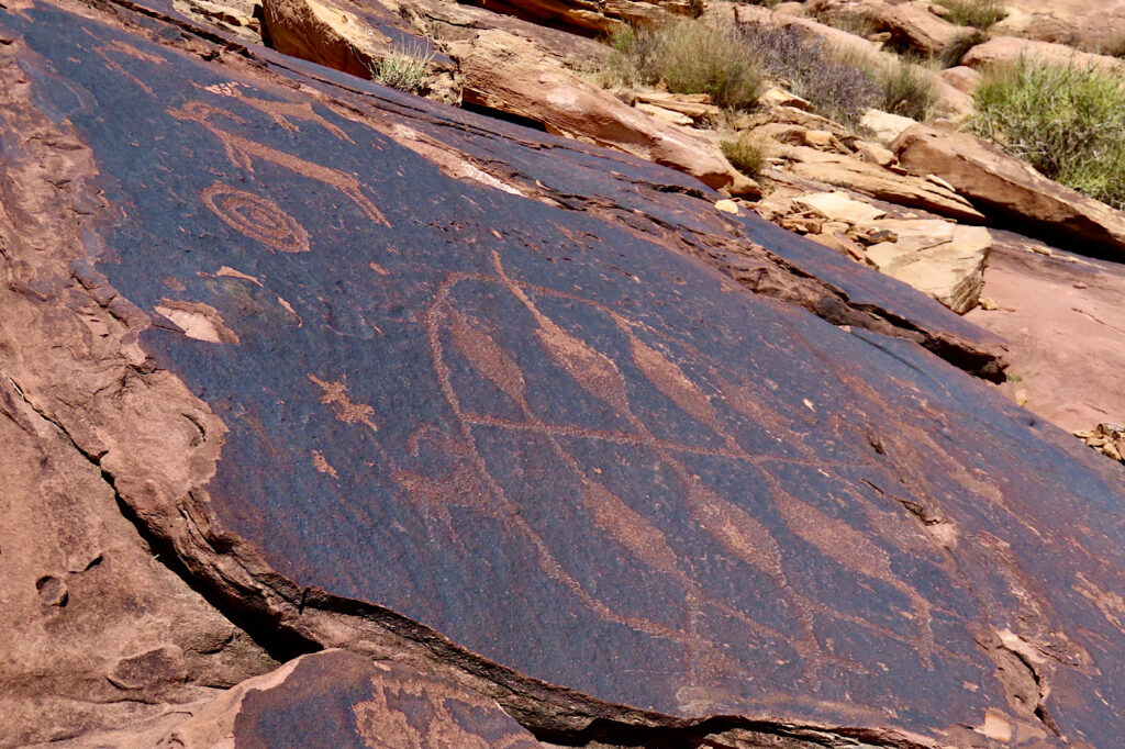 Ancient rock art drawing on dark black veneer on red rock.