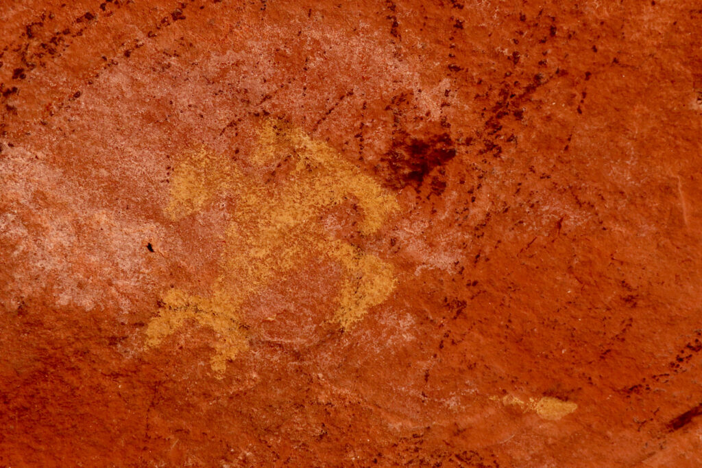 Ochre coloured image painted on red rock.