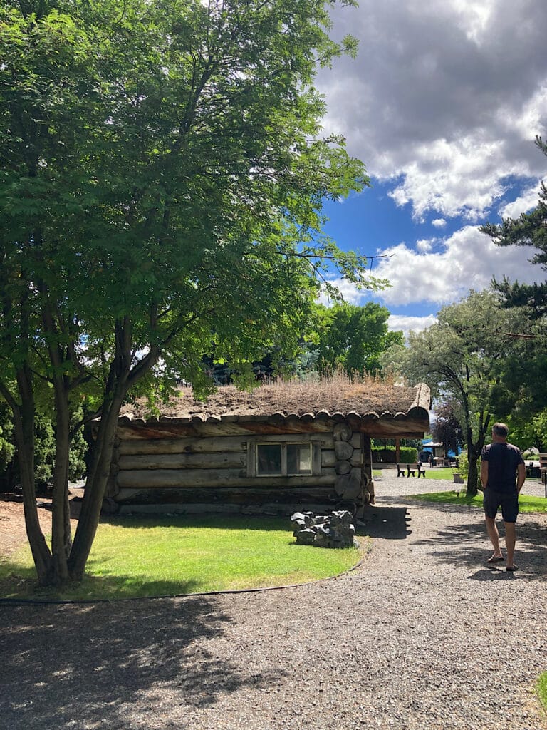 Man walking gravel path towards a log cabin.