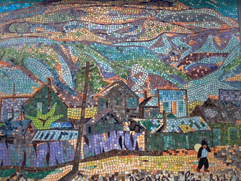 Mosaic image of town and tree and a person under big sky.