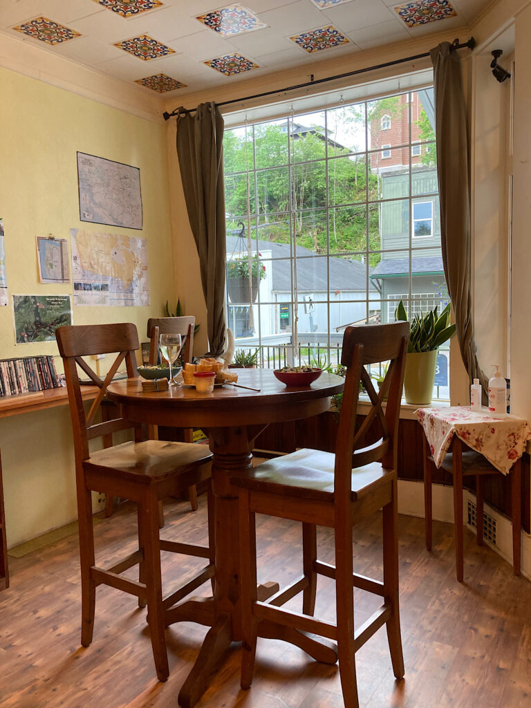 Small table and 2 tall chairs in front of a window.