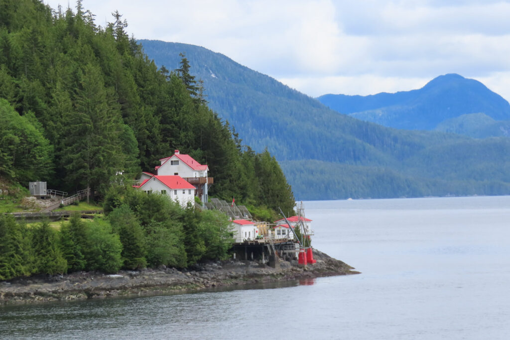 Red and white buildings perching on bluff overlooking water.