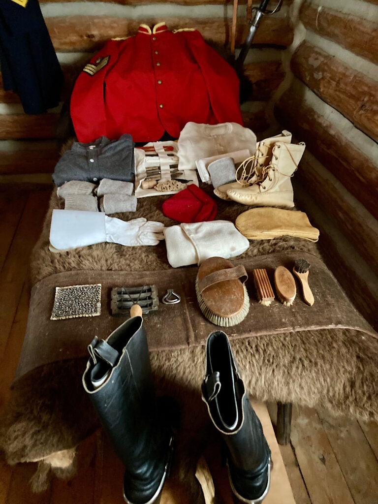 Clothing and artifacts laid out on a bed covered with a brown buffalo hide.