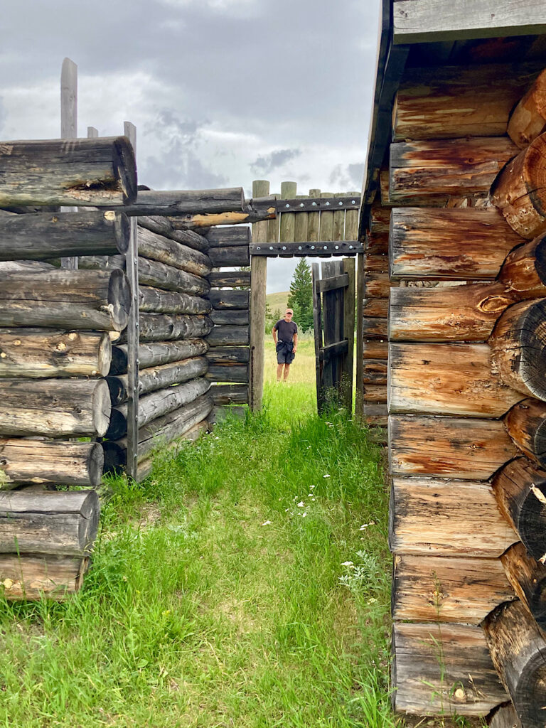 Man standing in doorway of log structure.