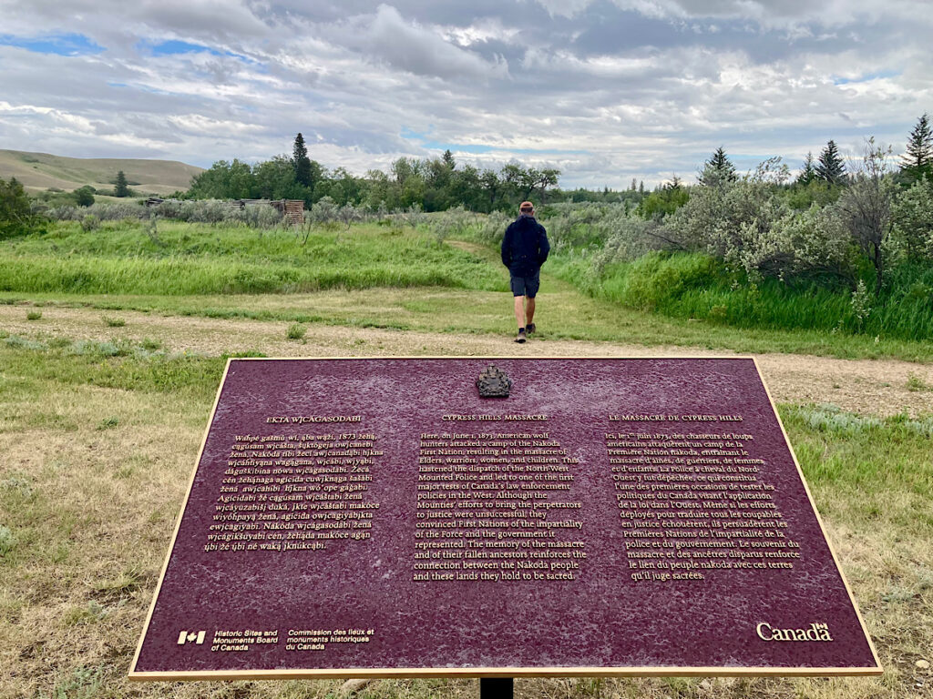 Man walking behind interpretive sign under grey skies.