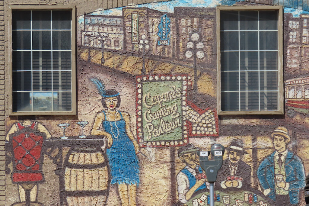 Painting of woman from 1930s standing at bar with image of Al Capone and his rum runners.