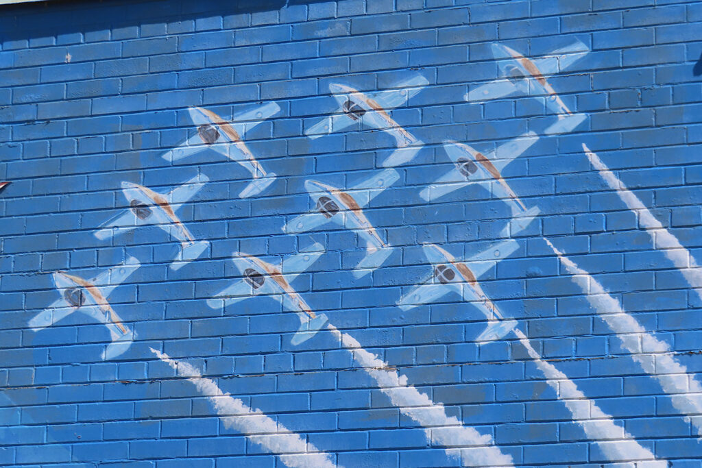 Painting of white jets in formations on blue background.