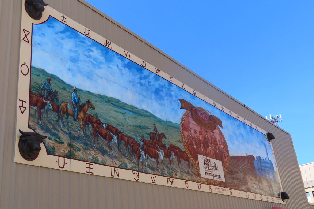 Mural of cattle, cowboys on horses and a train station.