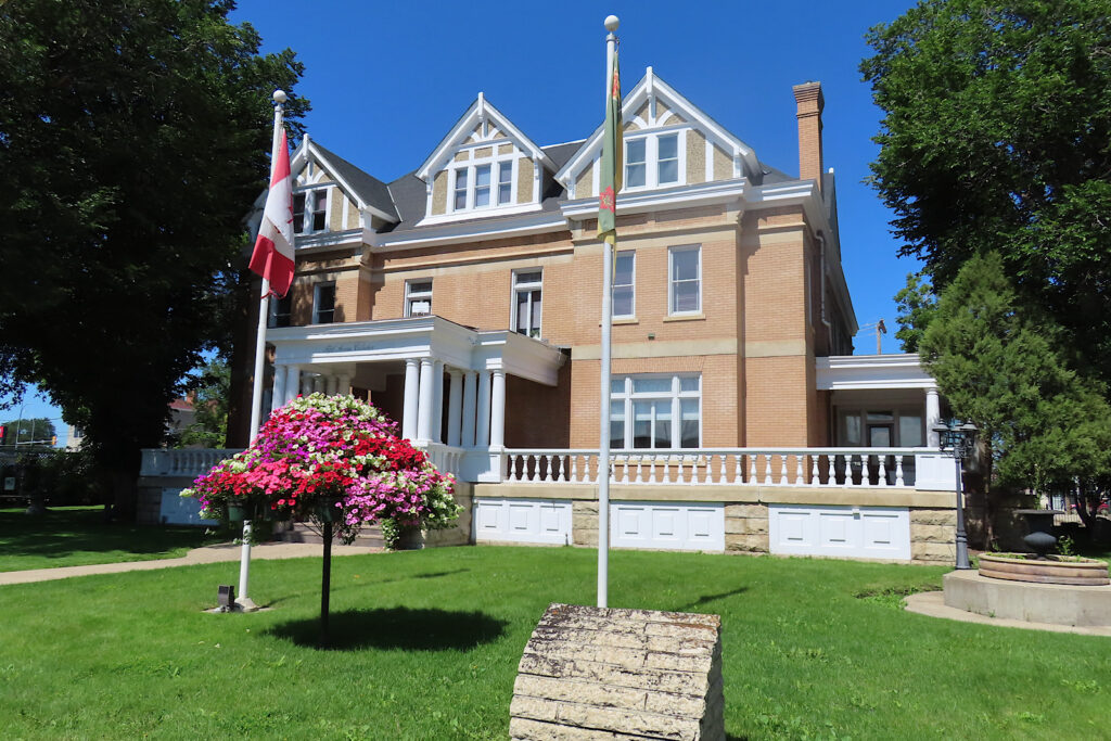 Large brick home with flagspoles on front grass.