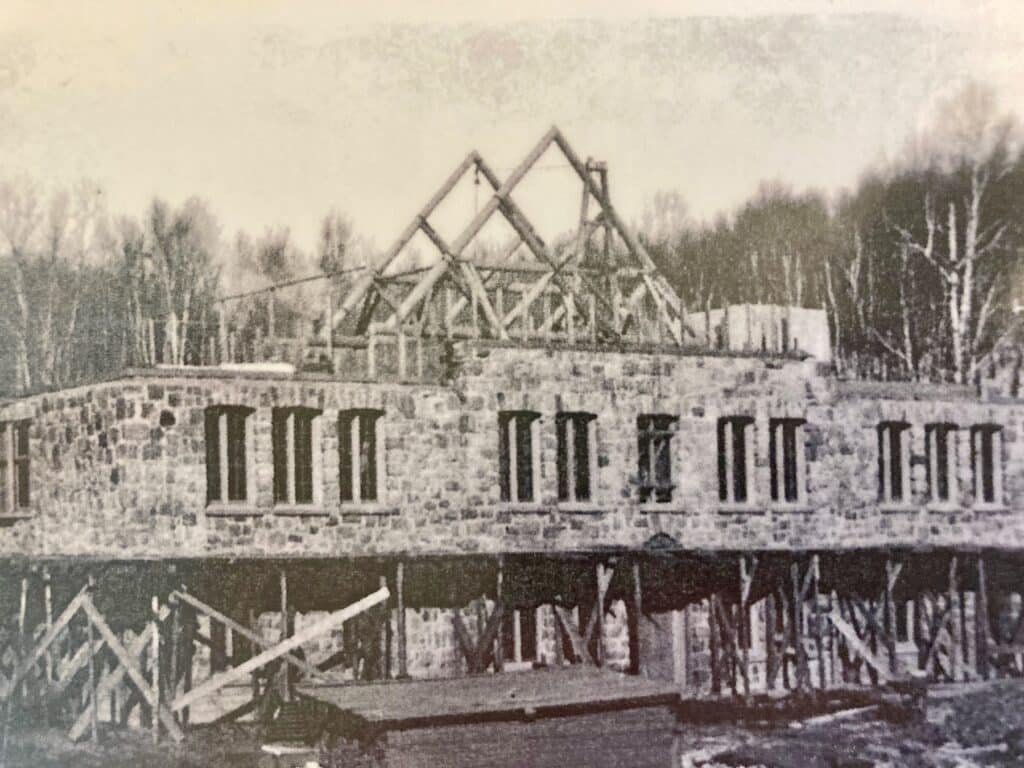 Black and white photo of large stone building being constructed.