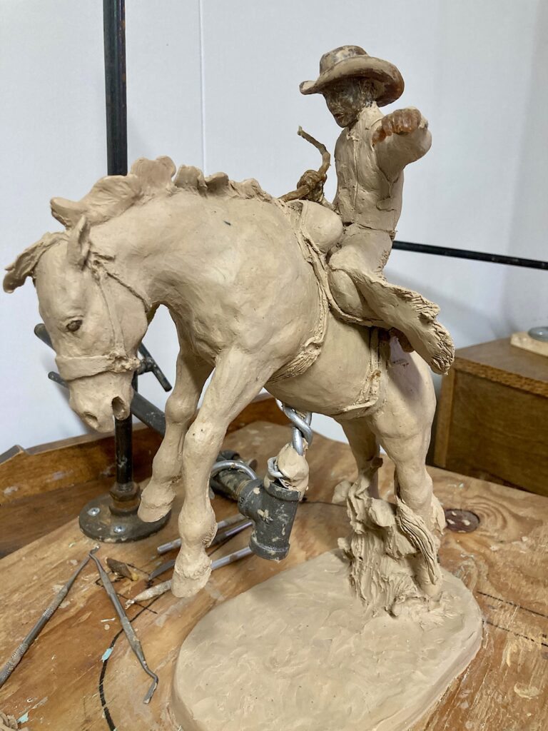 Sculpture of horse bucking and cowboy on his back.