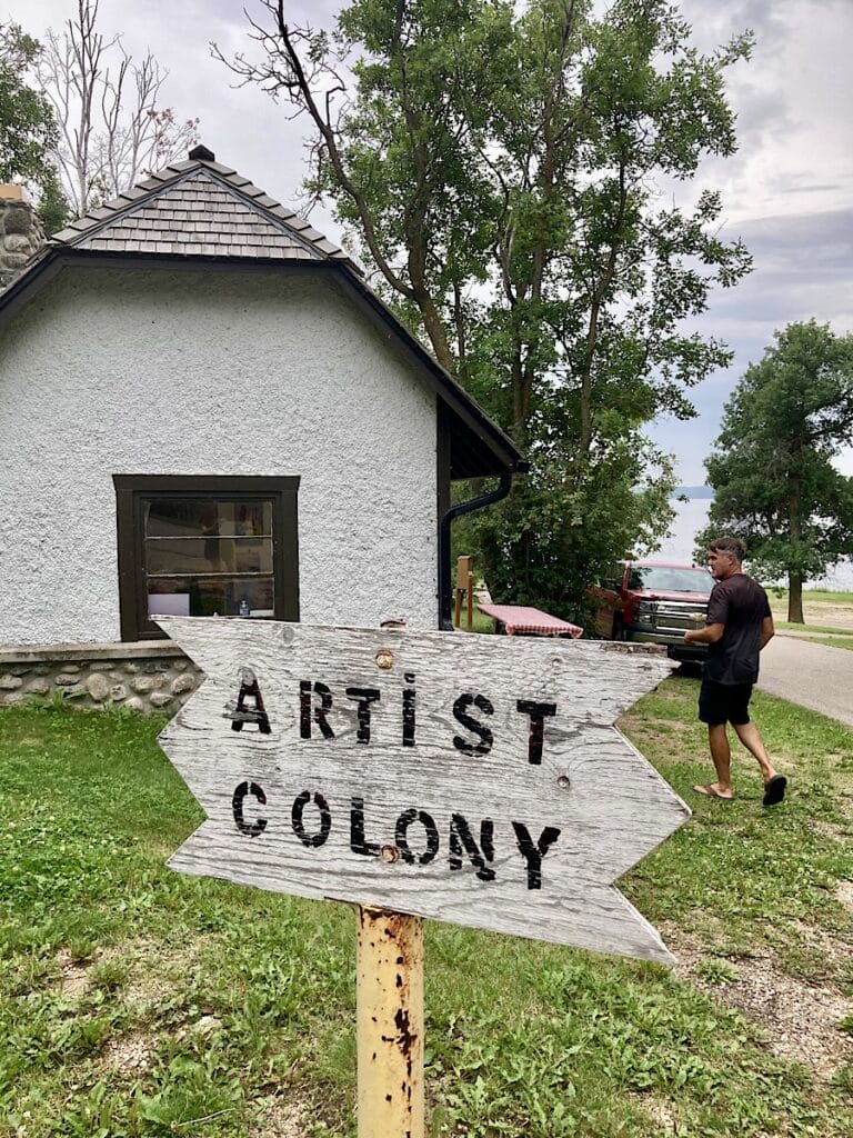 Man walking towards white building with sign reading: Artist Colony.