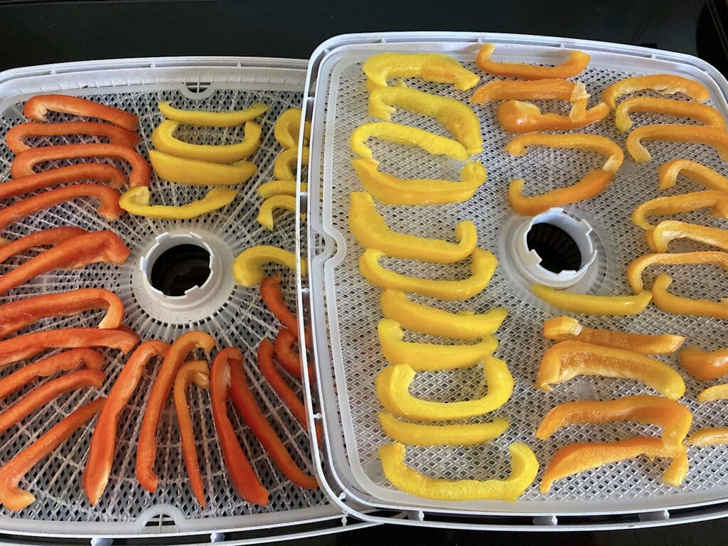 Image of red, yellow and orange pepper slices on white plastic trays.