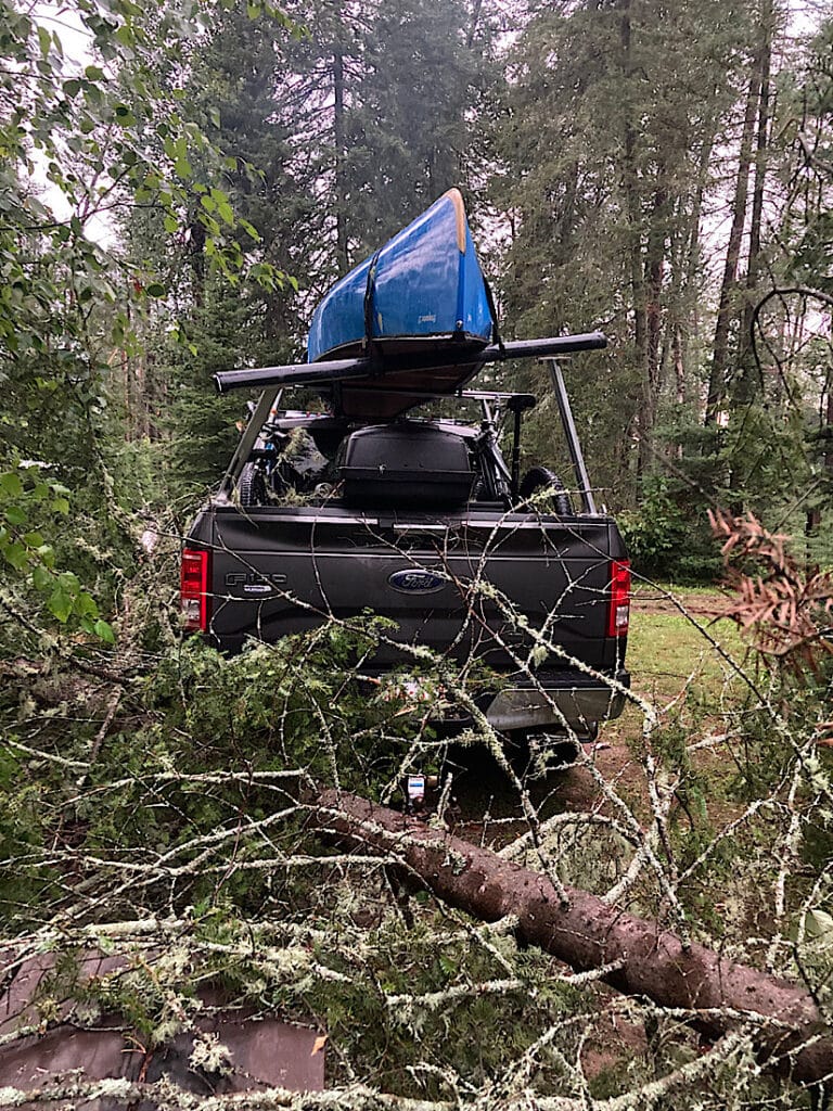 Fallen trip next to broken canoe rack holding blue canoe on truck.