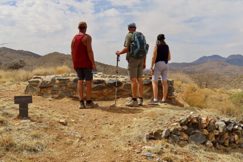 Two men and a woman standing overlooking a rock cistern.