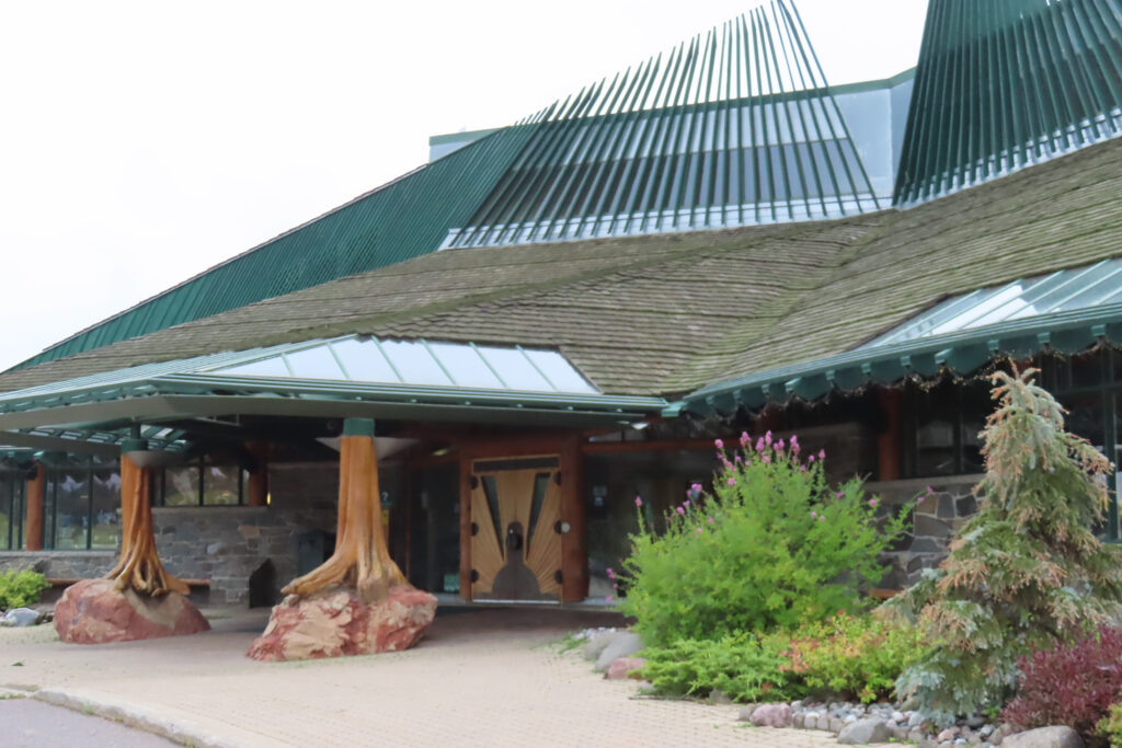Large building with large trees supporting entrance roof.