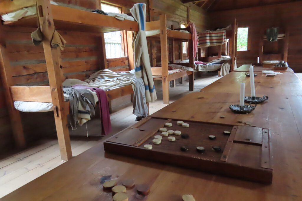 Wooden bunks in background with wooden game laid out on table in foreground.