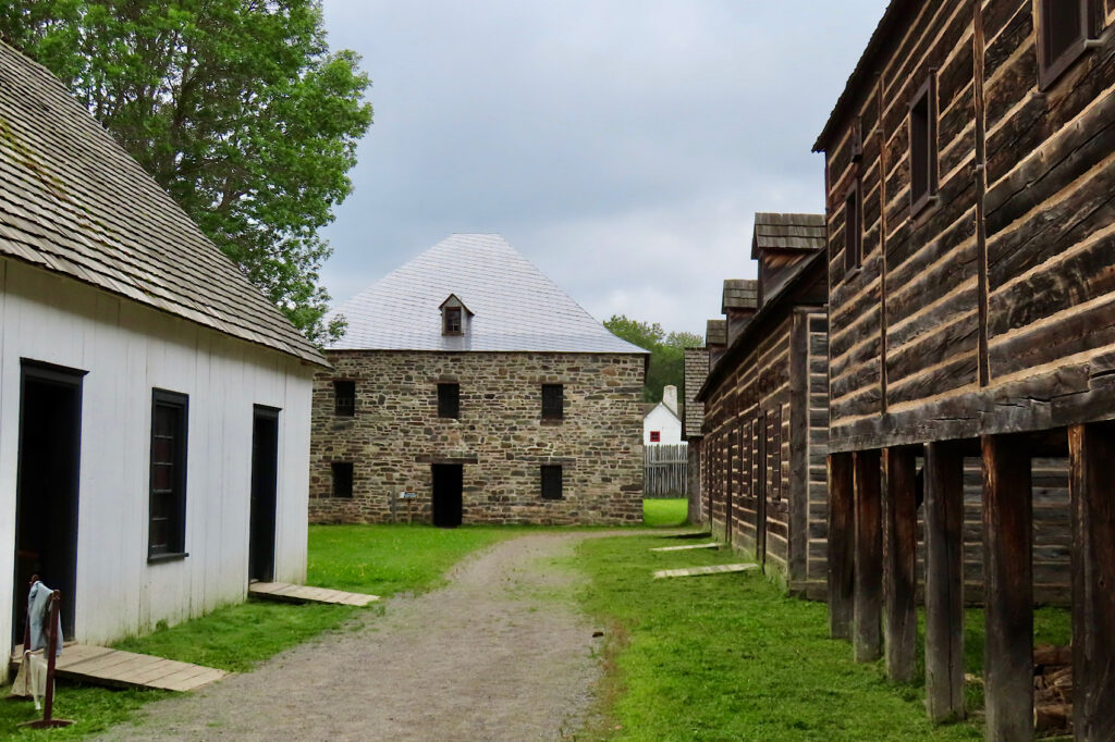 Stone, whitewashed and wooden buildings along dirt road.