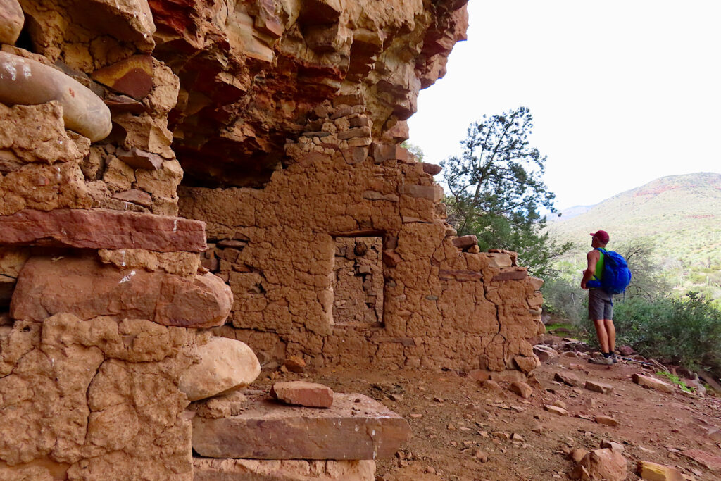 Man looking at rock wall with a window built into cliff side.