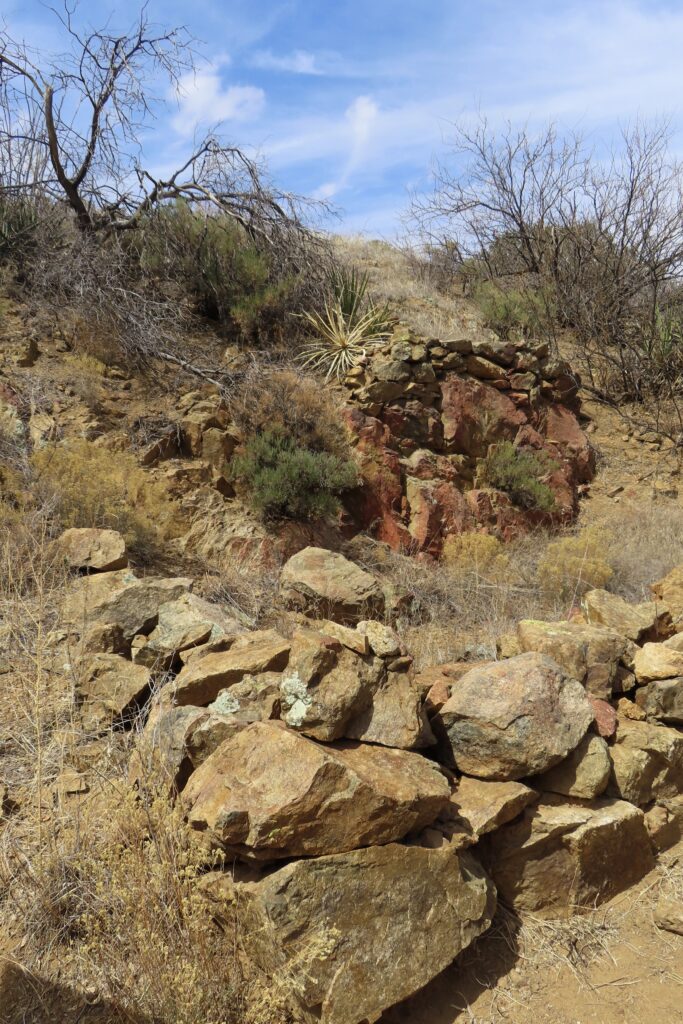 Pile of rock rubble around a depression in a hillside.