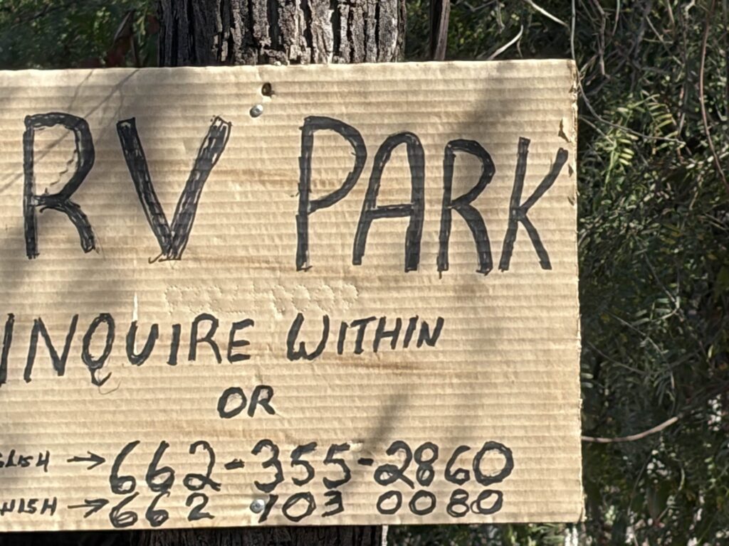 Cardboard sign RV Park, Inquire within and phone numbers.