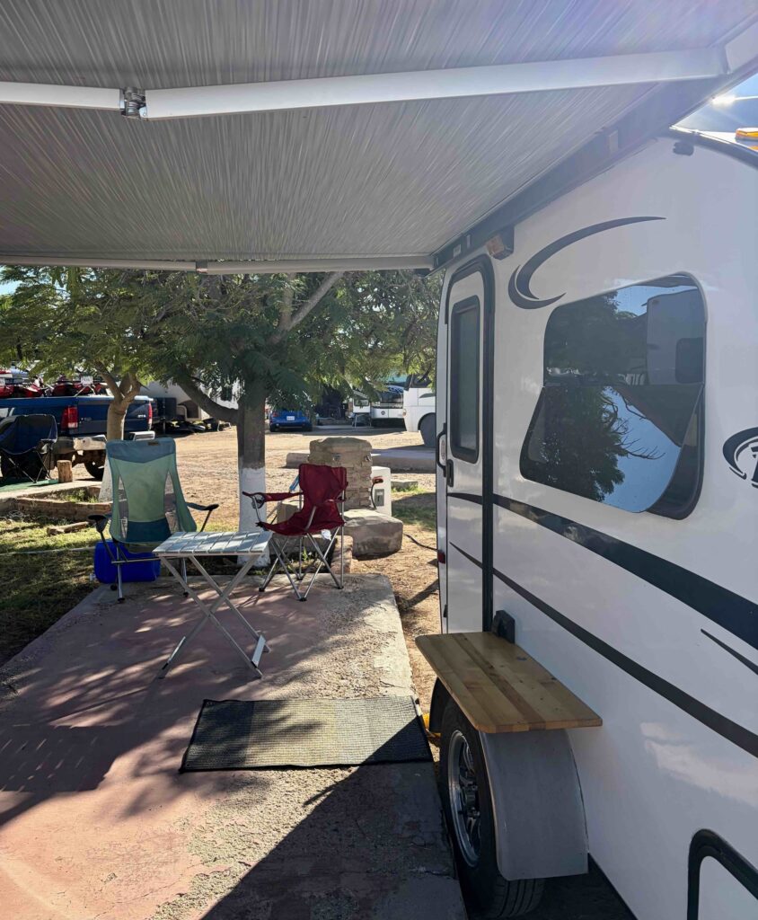 Small trailer set up with awning and two lawn chairs.